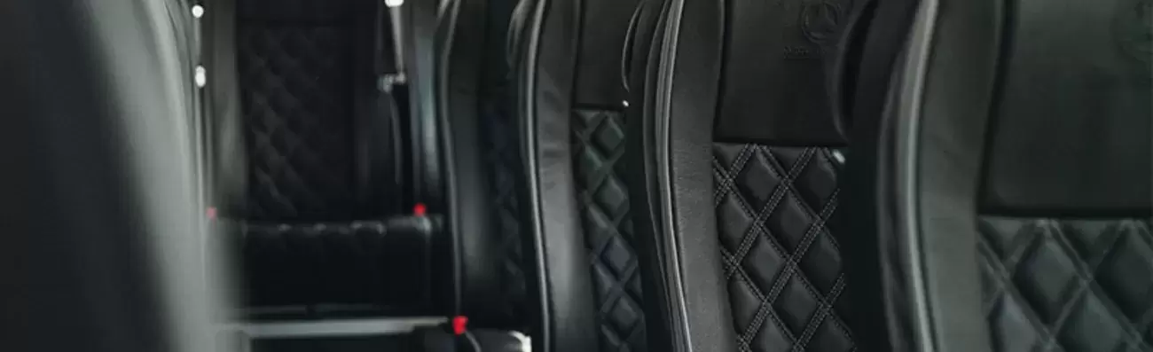 Luxury coach seats with black leather upholstery and diamond stitching.